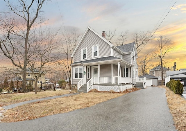 view of front of property featuring a garage, an outdoor structure, and covered porch