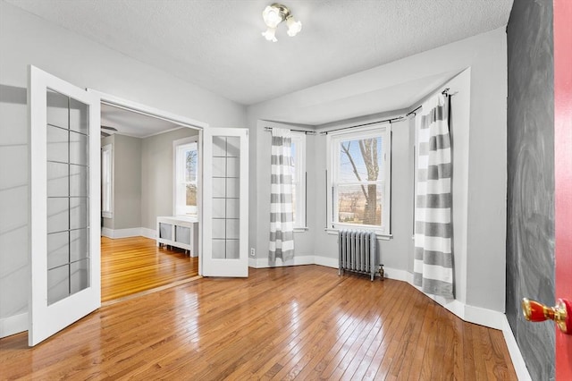 spare room with hardwood / wood-style flooring, radiator, a textured ceiling, and french doors