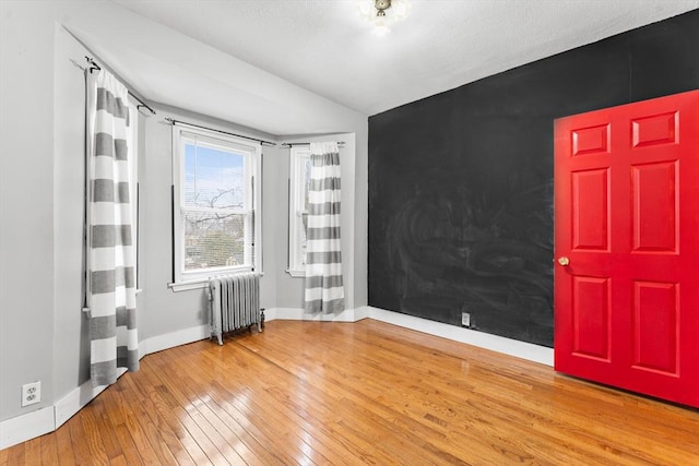 empty room with hardwood / wood-style flooring and radiator heating unit