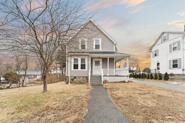 view of front of property with covered porch and a lawn