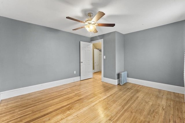 unfurnished bedroom featuring ceiling fan, radiator heating unit, and light wood-type flooring