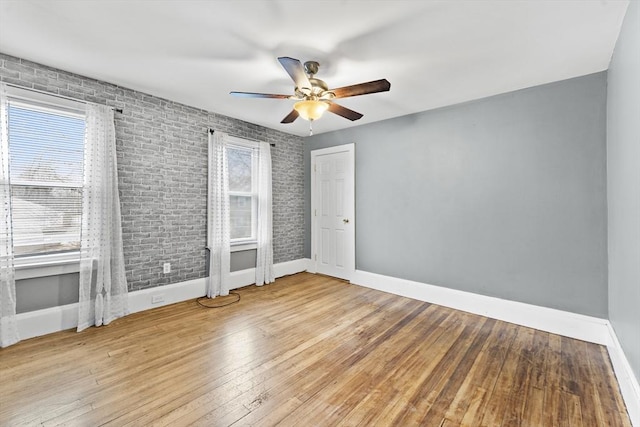 interior space featuring ceiling fan, brick wall, and light hardwood / wood-style flooring