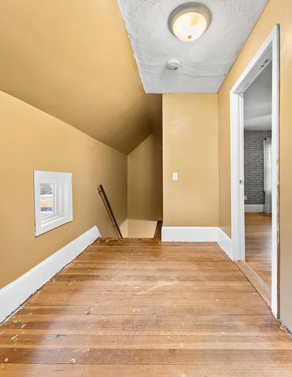 additional living space featuring lofted ceiling and wood-type flooring