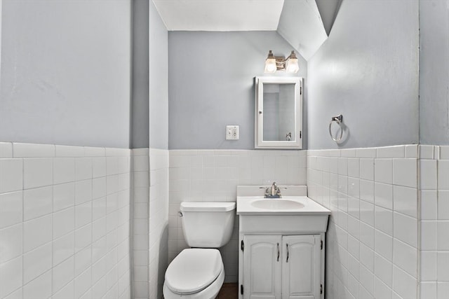 bathroom with vanity, tile walls, and toilet