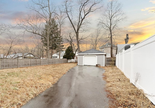 yard at dusk featuring a garage and an outbuilding