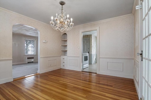 unfurnished dining area with built in shelves, hardwood / wood-style floors, radiator, and crown molding