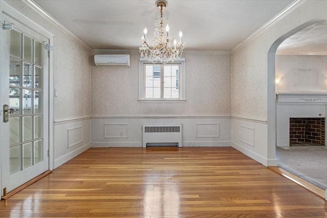 unfurnished dining area featuring hardwood / wood-style flooring, radiator heating unit, a wall mounted AC, and crown molding