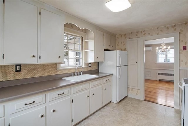 kitchen with sink, radiator heating unit, a wealth of natural light, and white cabinetry