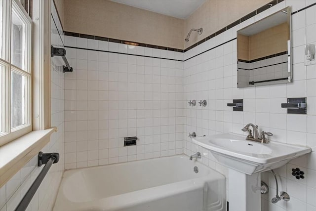 bathroom with tiled shower / bath combo and tile walls