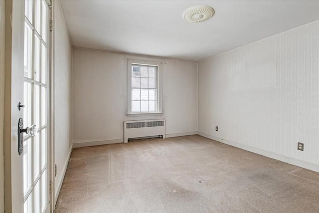 unfurnished room with light colored carpet and radiator heating unit