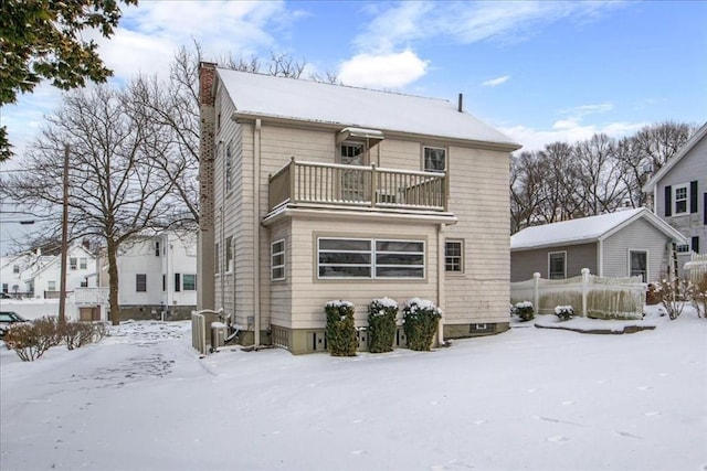 snow covered rear of property featuring a balcony