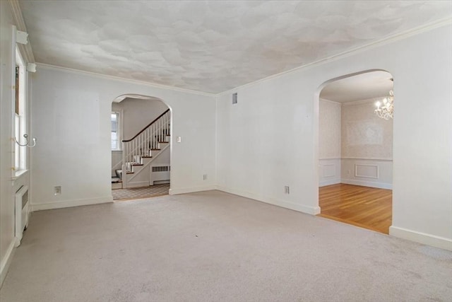 spare room with light carpet, radiator, and ornamental molding