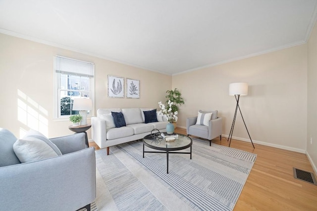 living area with baseboards, visible vents, wood finished floors, and ornamental molding