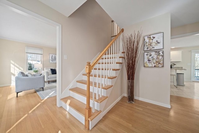 staircase featuring baseboards and wood finished floors