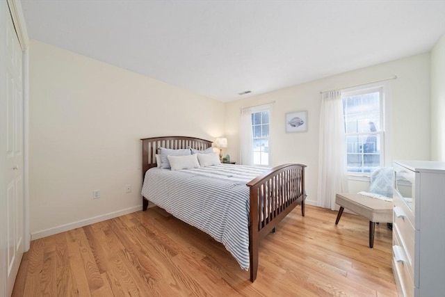 bedroom featuring visible vents, light wood-style flooring, and baseboards