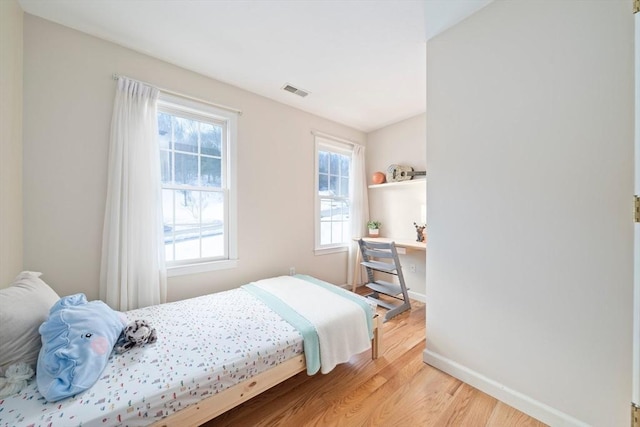 bedroom featuring baseboards, visible vents, and light wood finished floors