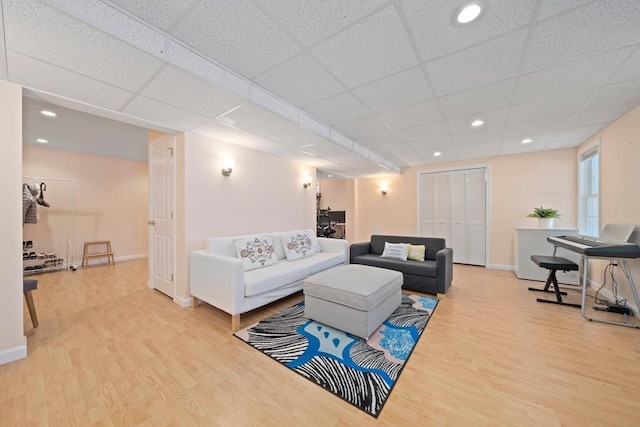 living area with recessed lighting, a drop ceiling, baseboards, and wood finished floors