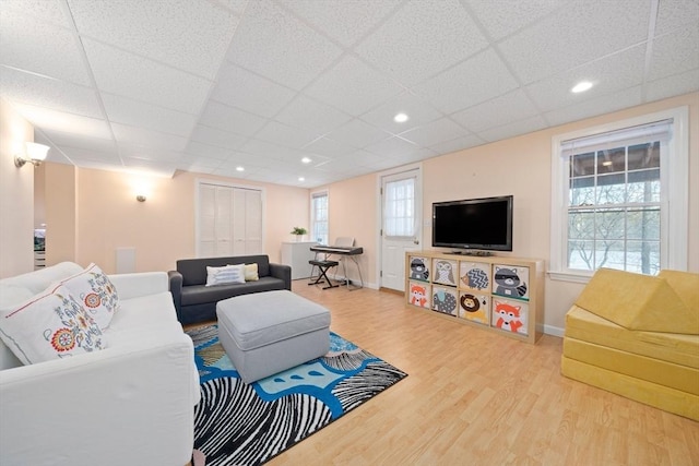 living area featuring recessed lighting, a paneled ceiling, baseboards, and wood finished floors