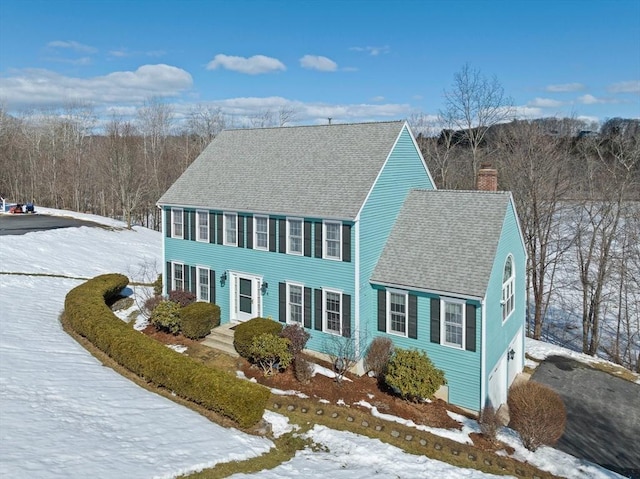 view of front of house with a shingled roof and a chimney