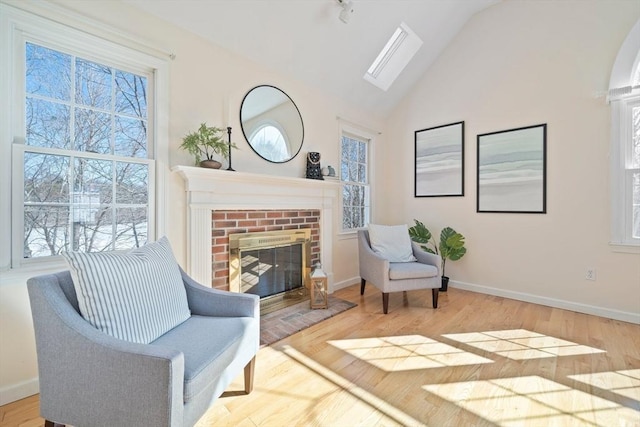 sitting room featuring plenty of natural light, wood finished floors, and a brick fireplace