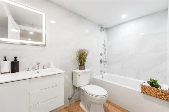 86 Cypress St Unit 8-6, Watertown, MA 02472 - bathroom featuring wood finished floors, toilet,  shower combination, vanity, and tile walls