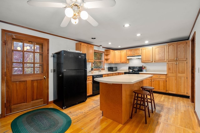 kitchen featuring light hardwood / wood-style floors, sink, black appliances, and a center island