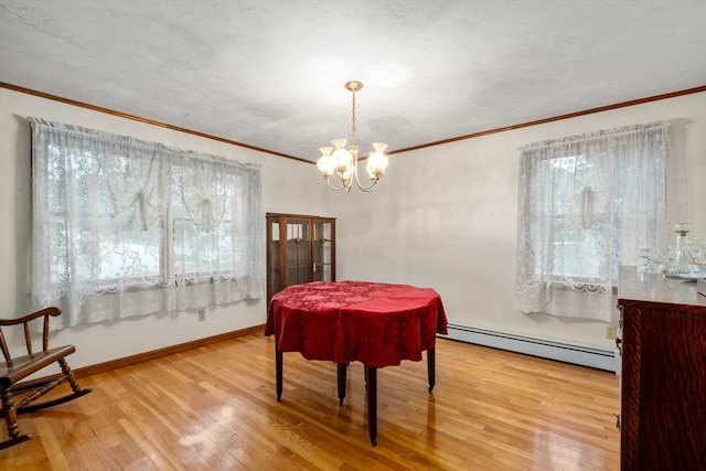 dining space featuring a chandelier, a baseboard radiator, light wood-type flooring, and crown molding