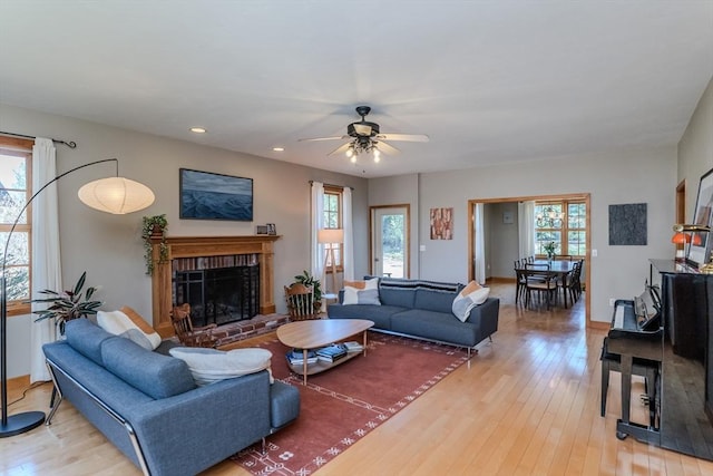 living area featuring a healthy amount of sunlight, a ceiling fan, and light wood-type flooring