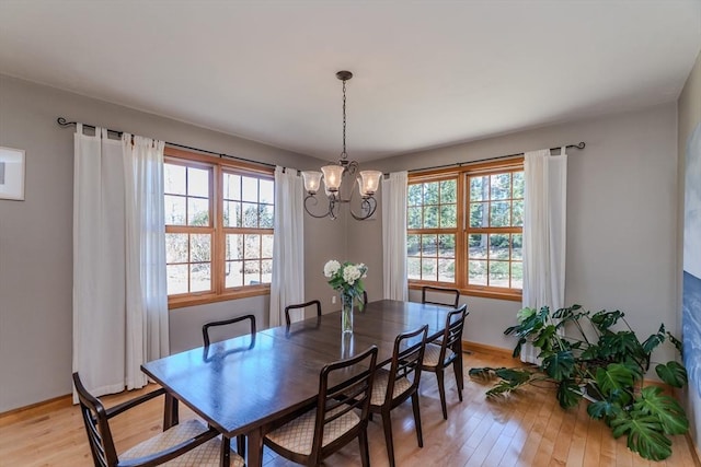 dining area with baseboards, a chandelier, a wealth of natural light, and light wood-style flooring
