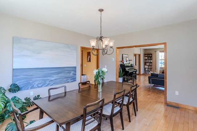 dining area with light wood-style floors, baseboards, a chandelier, and visible vents