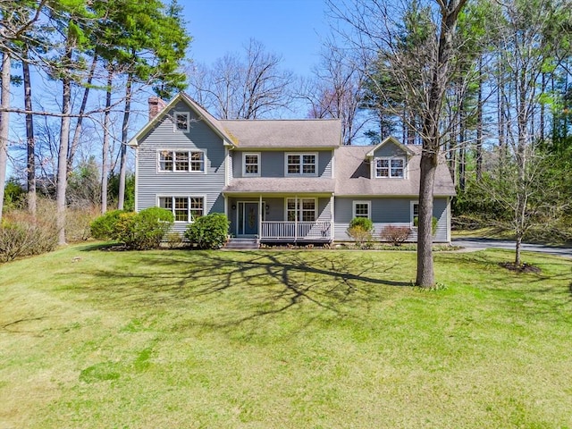 view of front of house featuring a shingled roof, covered porch, a chimney, and a front lawn