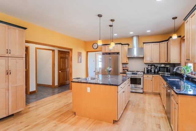 kitchen with light wood-style floors, a sink, appliances with stainless steel finishes, and wall chimney range hood