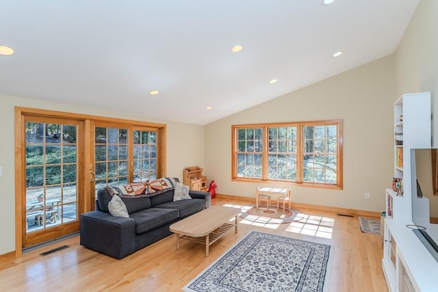 living room with visible vents, light wood finished floors, lofted ceiling, and a wealth of natural light