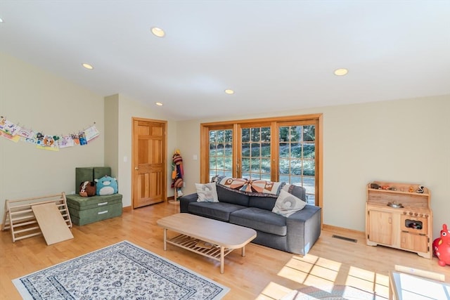 living room with light wood-style floors, recessed lighting, vaulted ceiling, and visible vents
