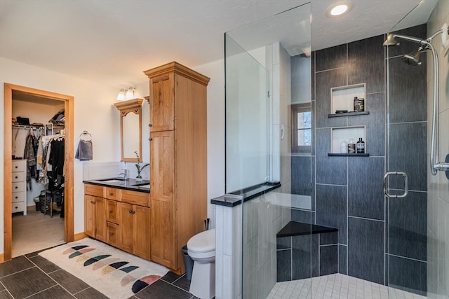bathroom with vanity, a stall shower, toilet, and a spacious closet