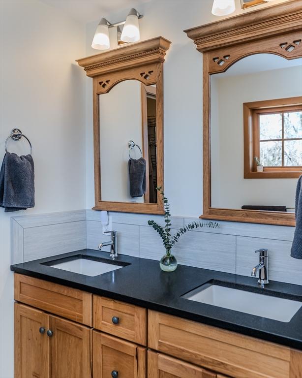 bathroom featuring a sink, backsplash, and double vanity