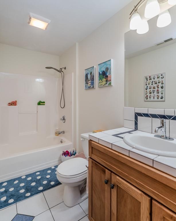 bathroom featuring tile patterned flooring, vanity, toilet,  shower combination, and visible vents