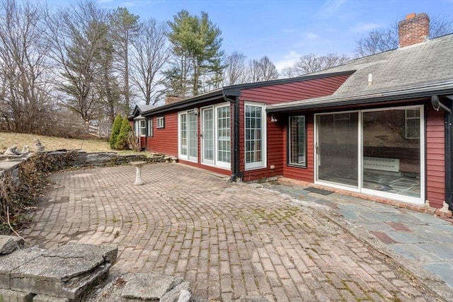 back of property with a chimney and a patio area
