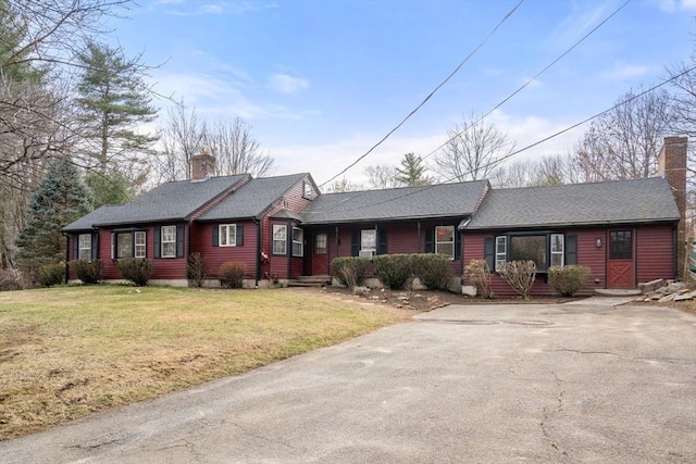 single story home with a front yard, a shingled roof, aphalt driveway, and a chimney