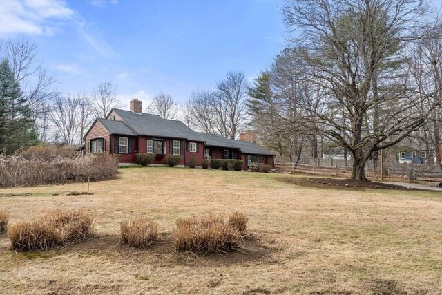 view of front of house featuring a front lawn, a chimney, and fence