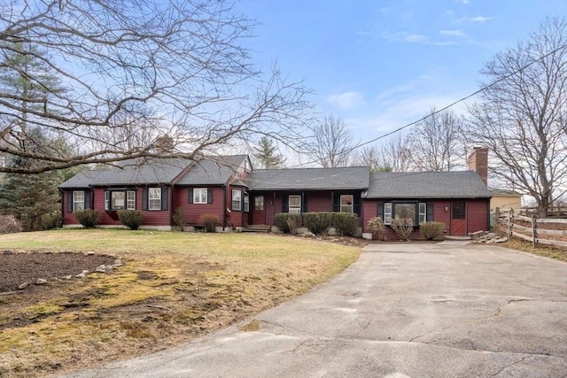 ranch-style house featuring a front yard, driveway, fence, and a chimney