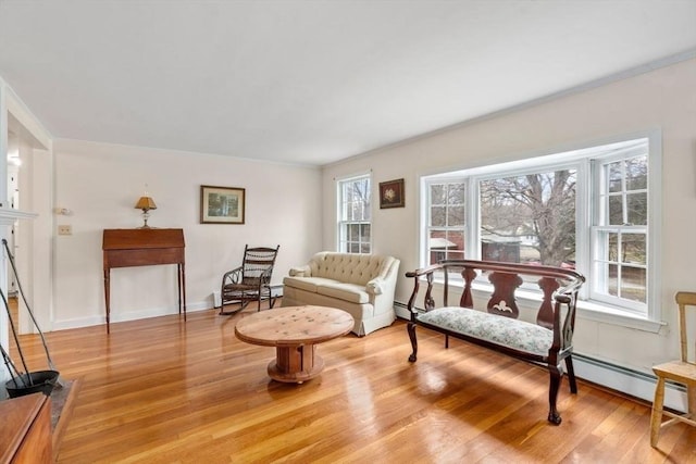 living area with light wood-style flooring, crown molding, baseboards, and a baseboard heating unit