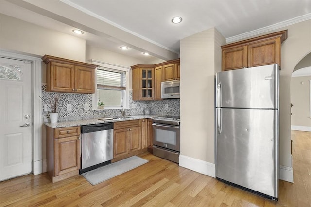 28 Mason, Salem, MA 01970 - kitchen featuring appliances with stainless steel finishes, brown cabinets, decorative backsplash, light stone counters, and light wood-type flooring