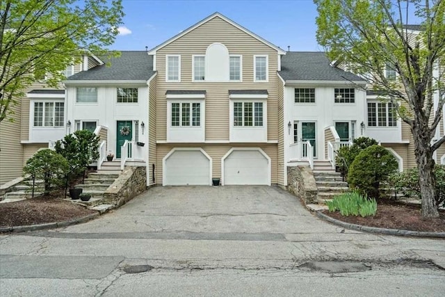 view of front facade featuring asphalt driveway, a garage, and a shingled roof