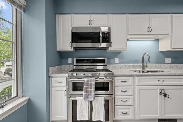 kitchen with appliances with stainless steel finishes, a sink, and white cabinets