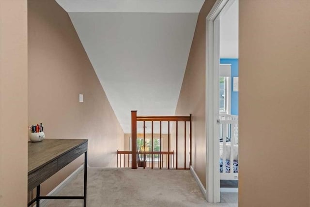 corridor featuring carpet floors, vaulted ceiling, healthy amount of natural light, and baseboards