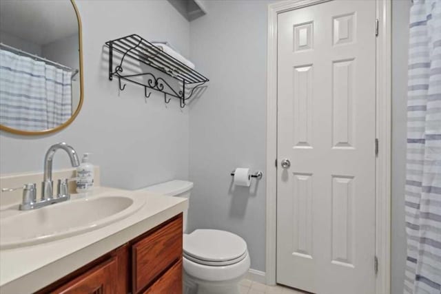 bathroom with toilet, vanity, and curtained shower