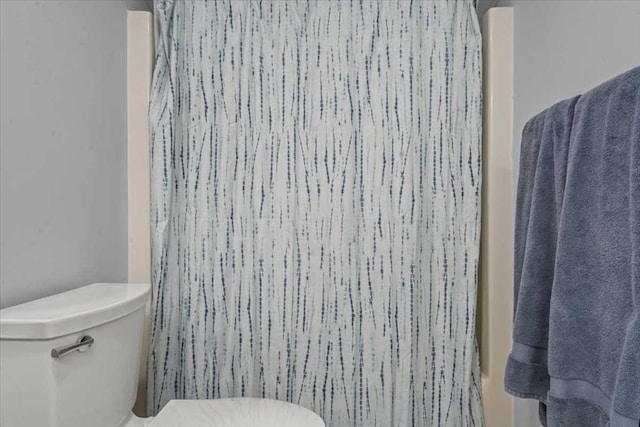 full bath featuring toilet and a shower with curtain