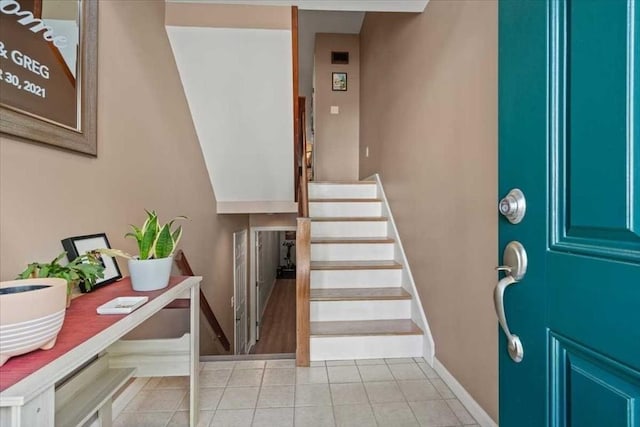 tiled foyer entrance with baseboards and stairs