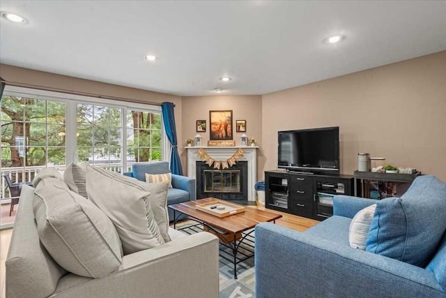 living area featuring a glass covered fireplace, recessed lighting, and light wood-style flooring